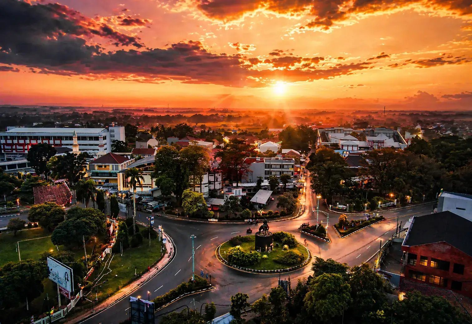 Pemandangan udara Purwokerto saat matahari terbit dengan bundaran ikonik dan lanskap kota Banyumas